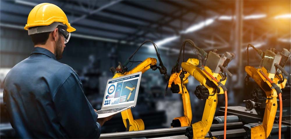 Ingeniero controlando robots industriales en una fábrica para asegurar la seguridad en máquinas.