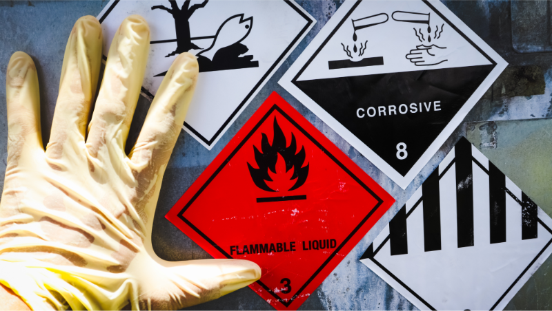 Consultoría en Prevención de Riesgos Laborales (PRL), imagen de señales de advertencia de líquidos inflamables y corrosivos con guante de protección.