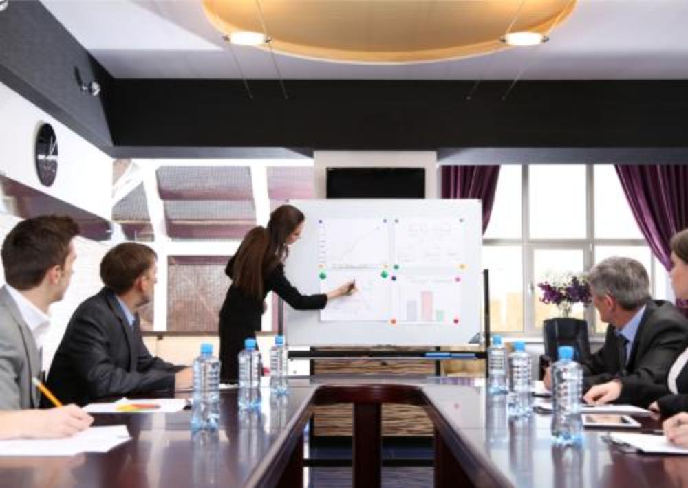 Consultoría en el área de formación, equipo de profesionales en sala de conferencias revisando gráficos en una pizarra blanca