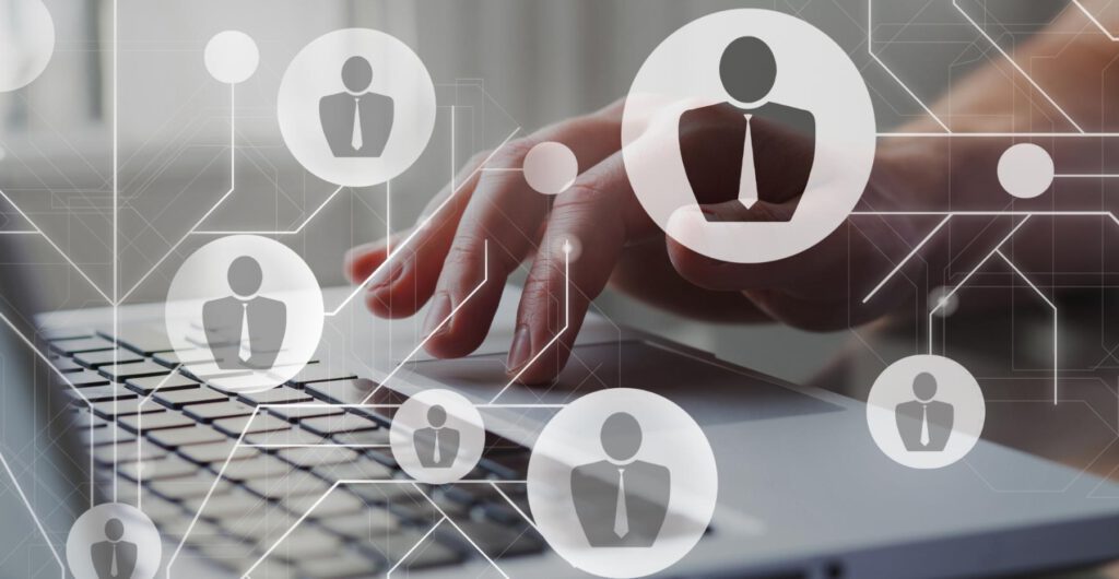 Manos tecleando en un portátil con iconos de conexiones empresariales y profesionales, representando la gestión de recursos humanos y redes de calidad en la empresa.