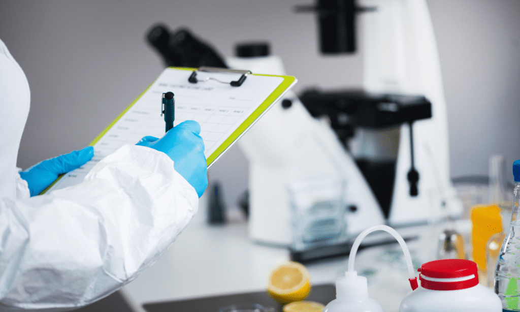 Técnico en seguridad alimentaria con equipo de protección revisando lista de verificación en laboratorio, asegurando el cumplimiento de normas de seguridad alimentaria.