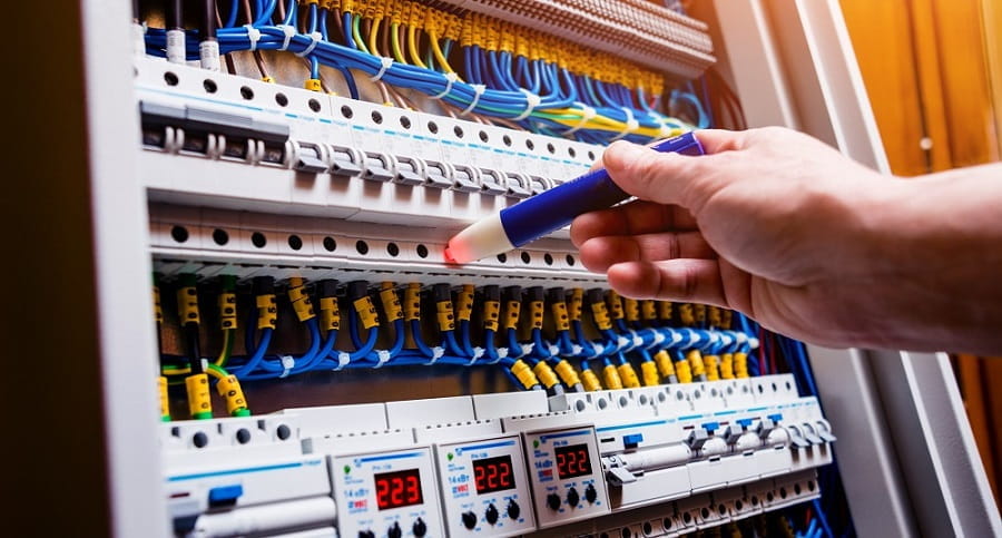 Mano de un técnico inspeccionando un cuadro eléctrico con un lápiz detector, representando la Nueva Orden 163/2024 sobre instalaciones eléctricas.
