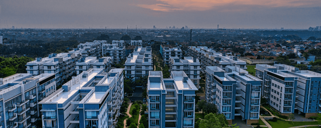 Vista aérea de un complejo de edificios residenciales al atardecer, representando los requisitos y periodicidades para las inspecciones OCA en instalaciones urbanas.